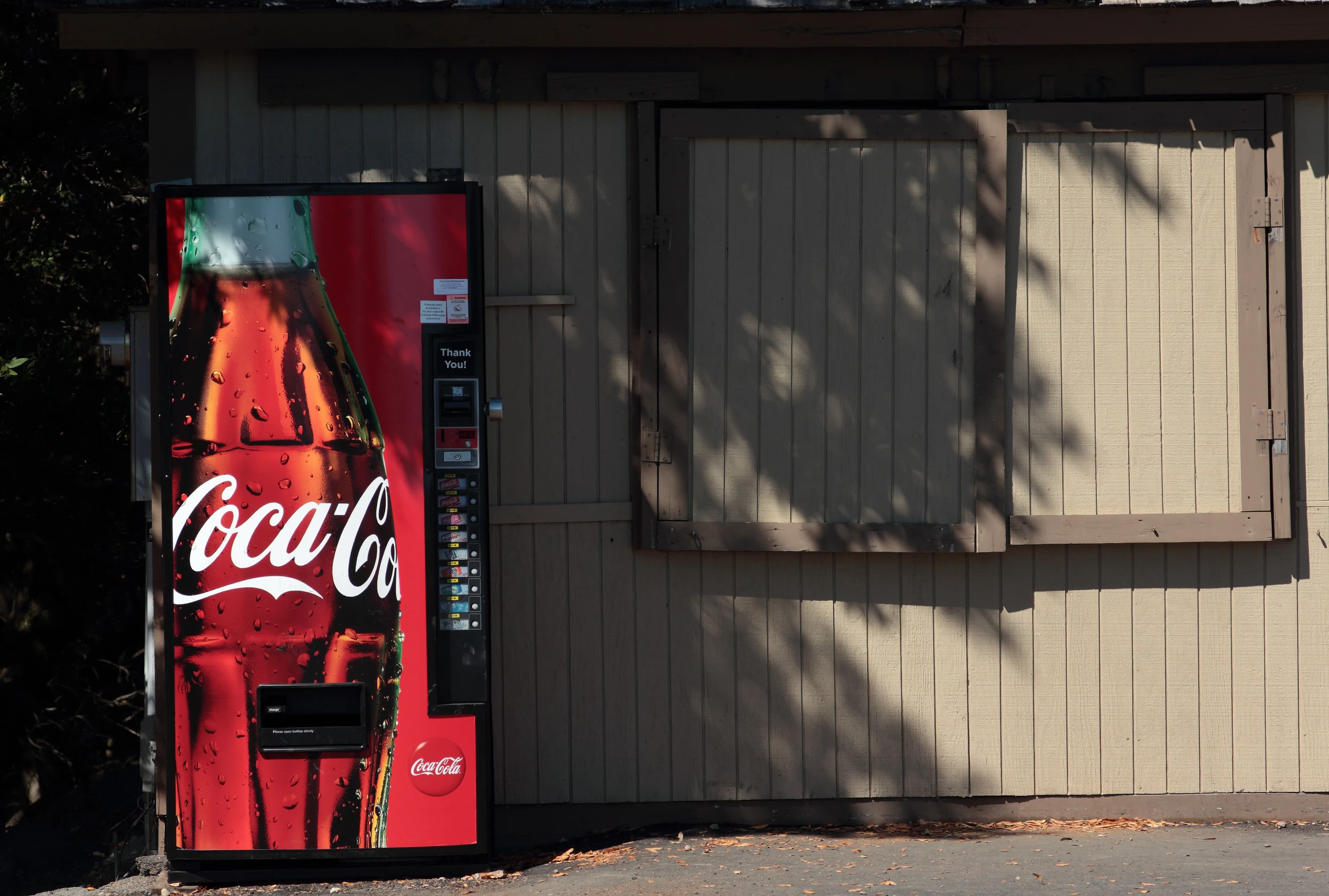 a coke machine next to a door with the words coca cola on it