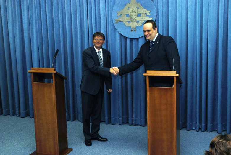 two men shake hands in front of podiums