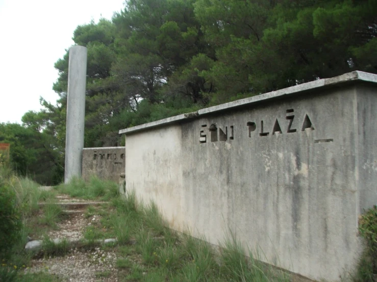 an old concrete sign sitting on top of a lush green hillside