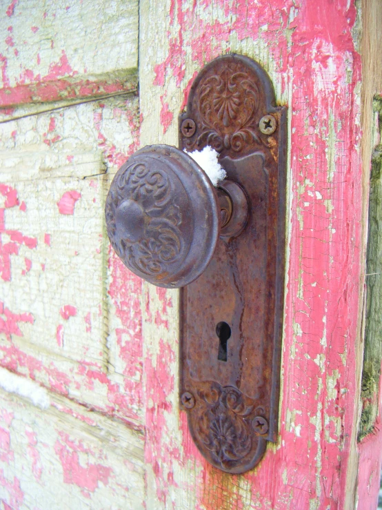 the rusty, ornate door is located on an old, dirty wooden door