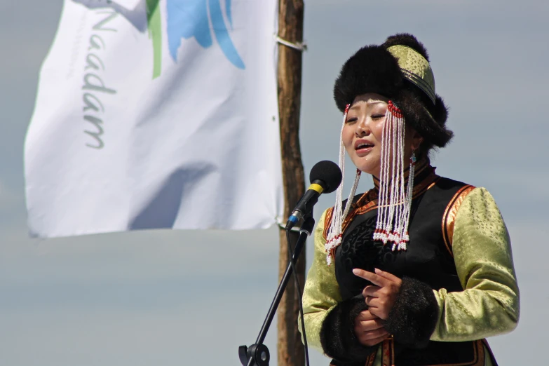 the woman wearing traditional clothing is speaking into a microphone