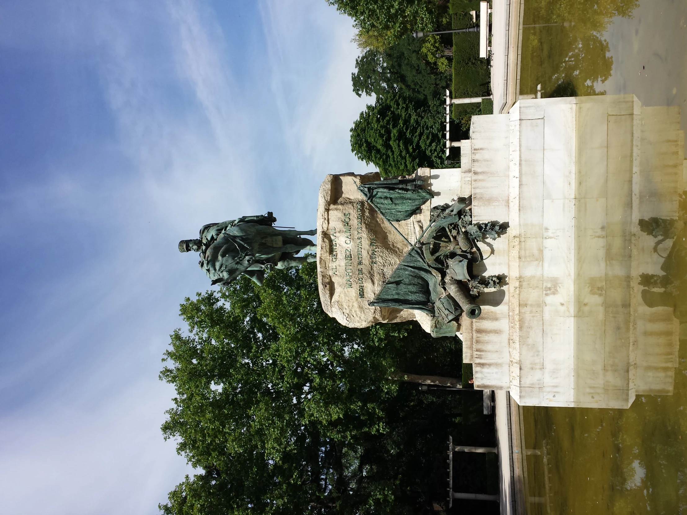 a statue stands in a pond surrounded by many trees