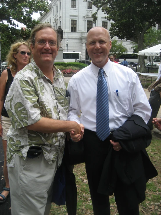 two older men wearing white shirts and blue tie standing side by side