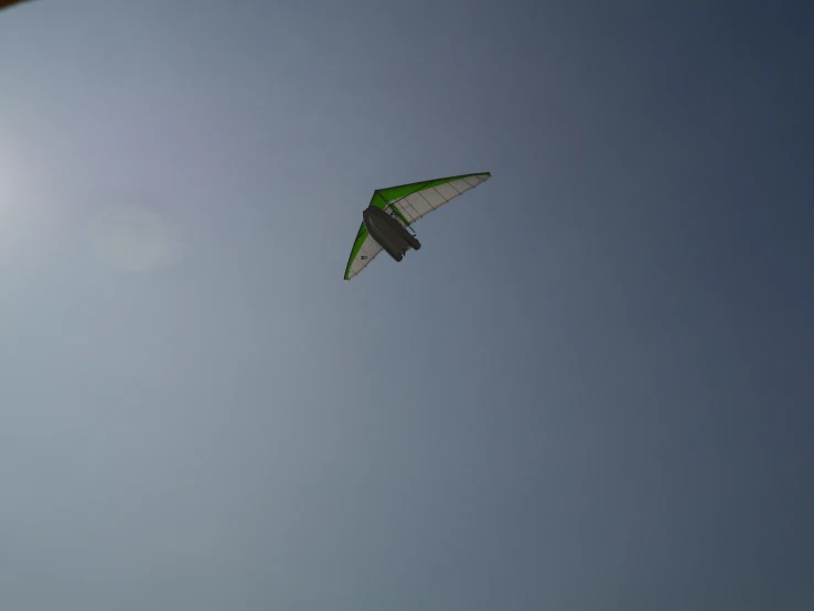 a green kite flying high up in the sky