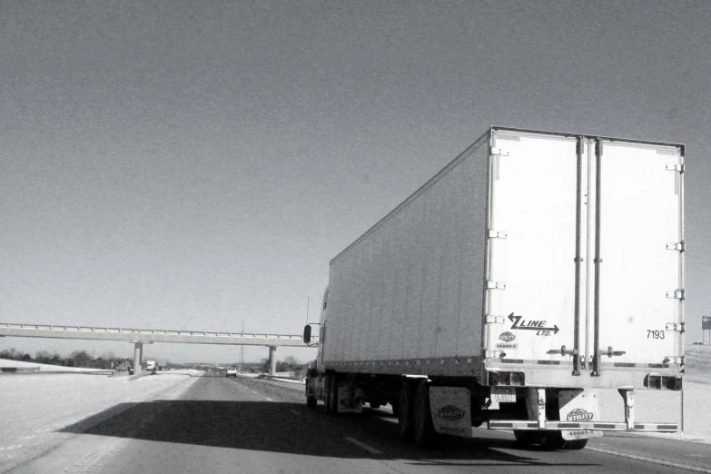 a truck moving on a freeway with road barrier in the background