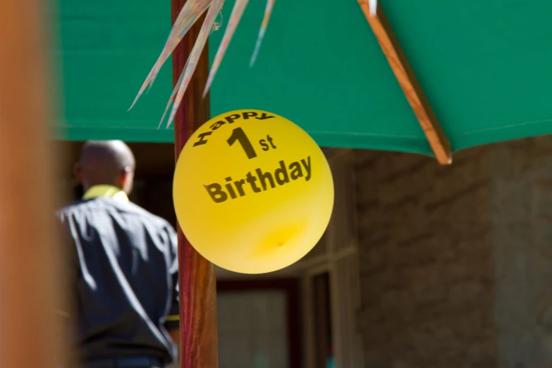 a yellow birthday ball attached to a green umbrella