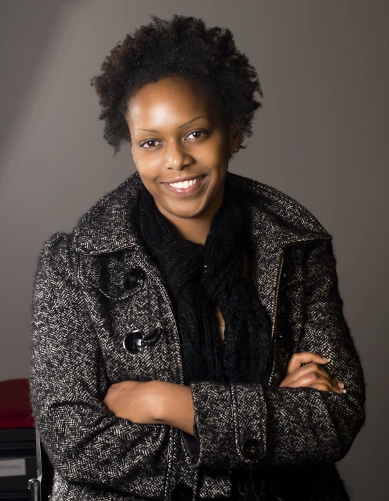 a woman that is wearing a coat standing with her arms crossed