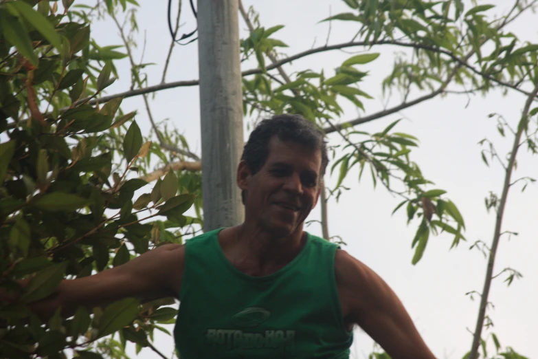 a man is standing next to trees while wearing a green shirt