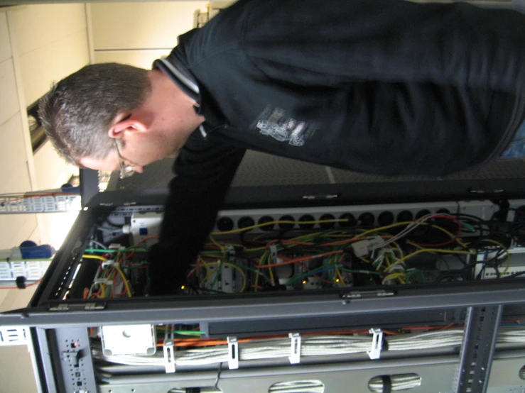 a man is trying to fix his network in the server's cabinet