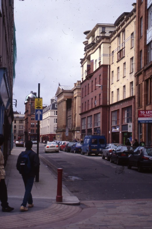 two men walk down a city street with buildings on either side