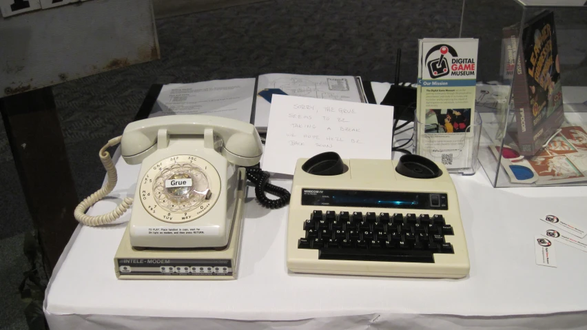 an old style telephone is next to a small keyboard and some typewriters