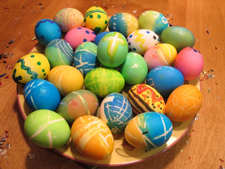 the plate has a bowl of colored decorated easter eggs