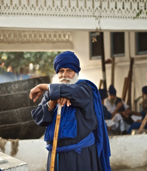 a man with a large blue turban is standing next to a building