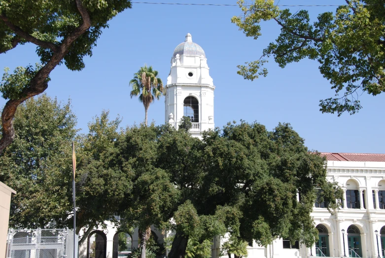 a large clock tower behind trees in front of a building