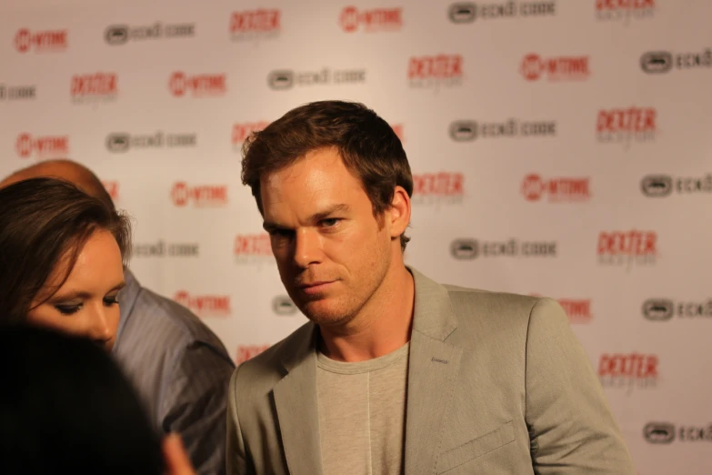 a man in a grey shirt a woman and a red carpet