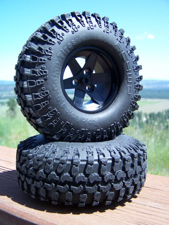 two tires and rims sitting on top of a wooden platform