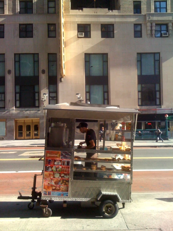 a man drives a street vendor cart in front of buildings