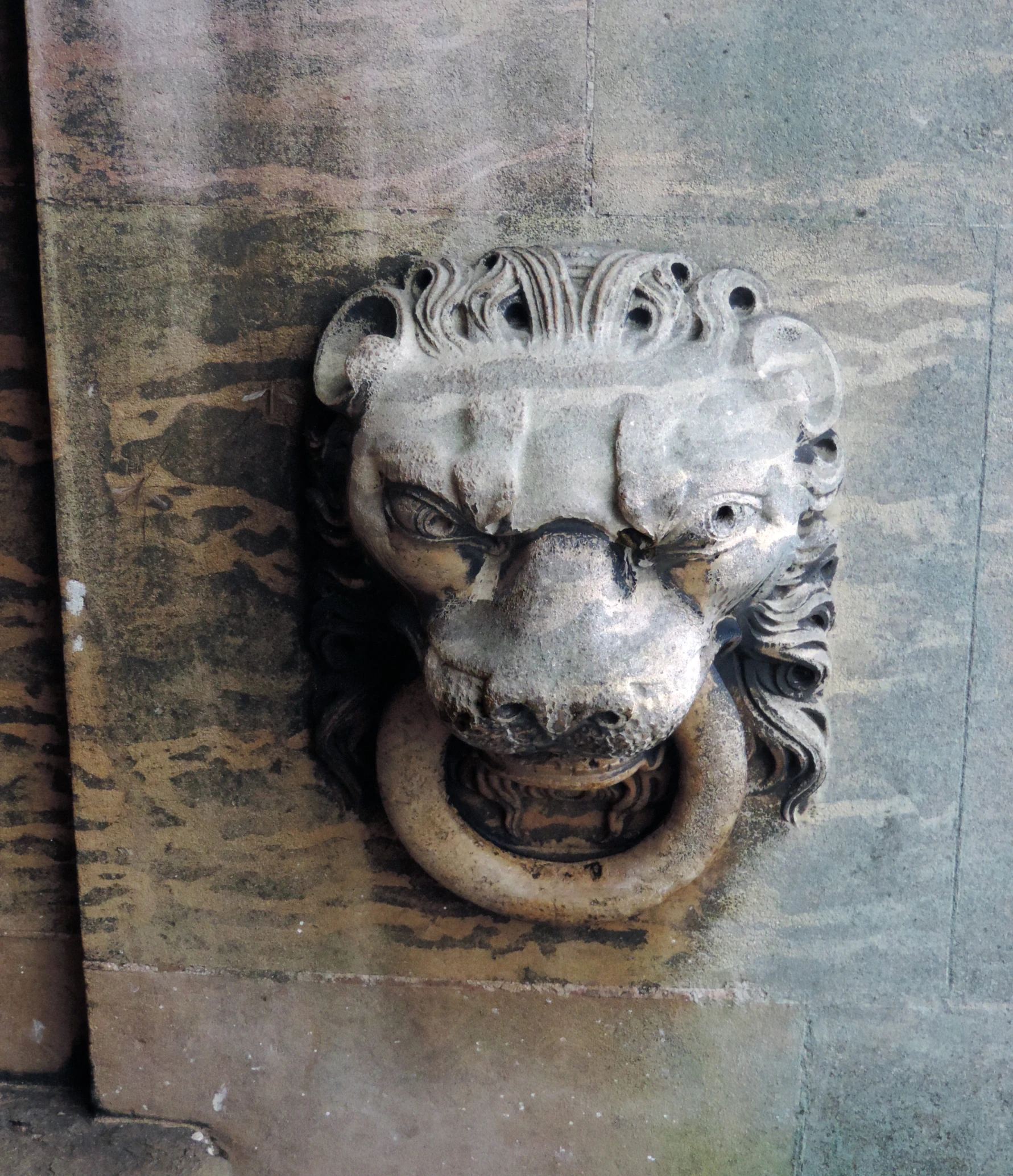 an intricate carving of a lion head on a concrete wall