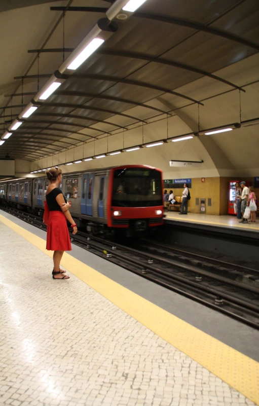 a train stopped at a subway station, as a woman stands by