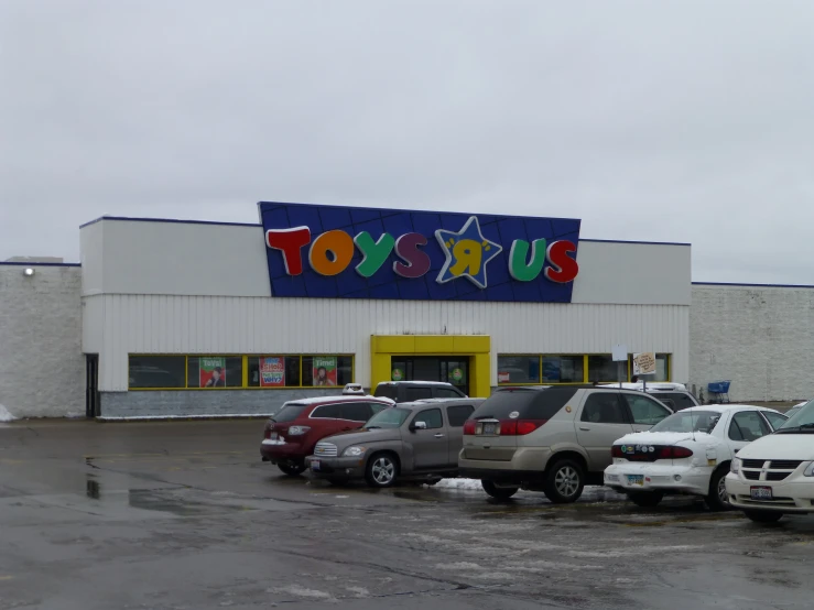 cars are parked in the parking lot outside of a toy store