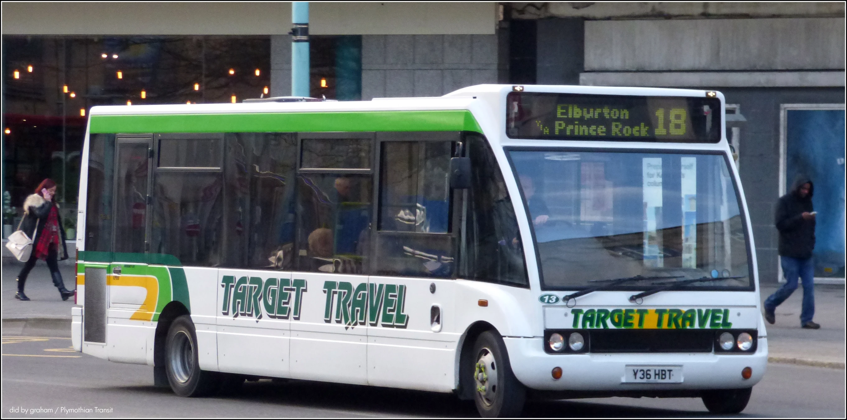 a green and white city bus in the street