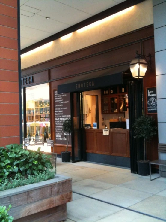 the front entrance of a large building with a bench and potted plant outside