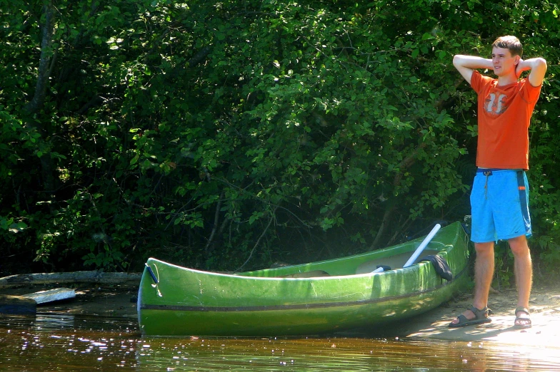 a man is standing beside a canoe on the shore