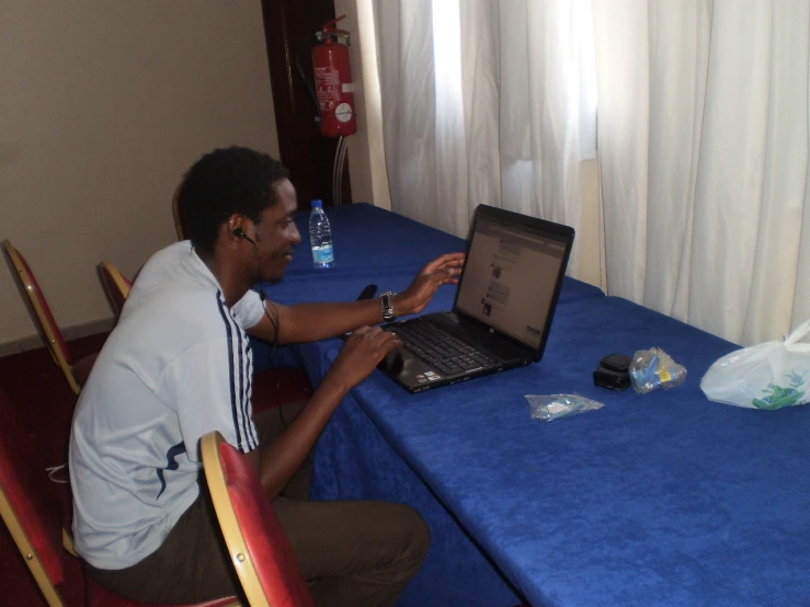 a young man uses a laptop on a table