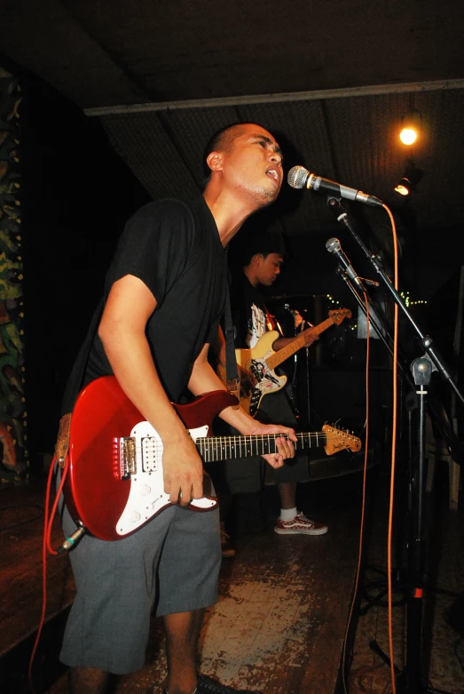 a man standing in front of a microphone playing a guitar
