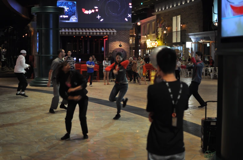 some people are dancing in a mall at night