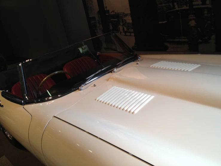 white convertible car parked in large space with its hood down