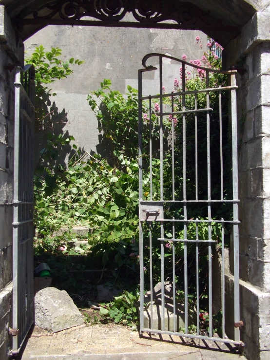 an open iron gate leading into a garden