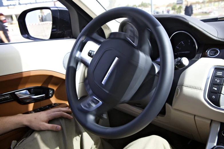 a man driving a car with an orange seat and beige dashboard