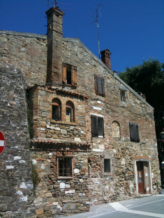 an old stone building with two balconies and a brick wall