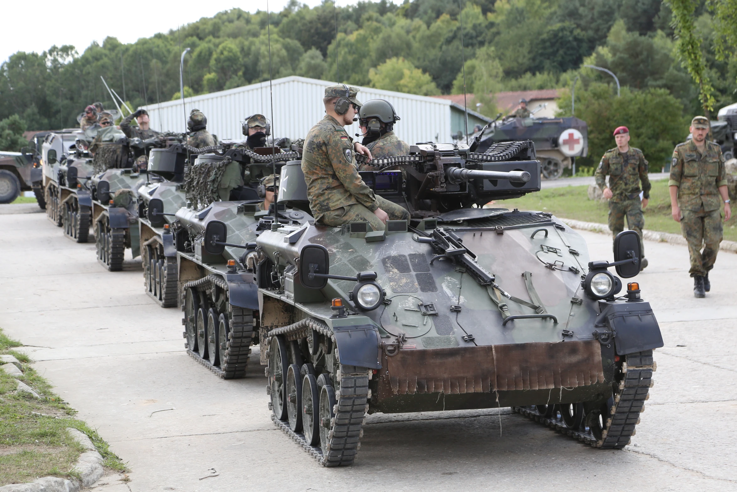 military men walking through a line of tanks