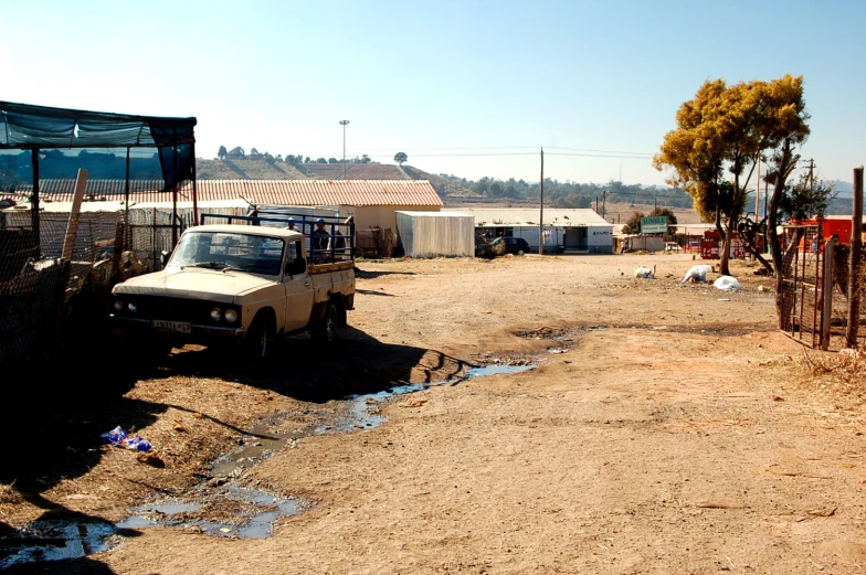 the dirt road is very dry with a parked car in it