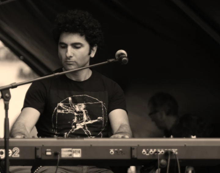 a man playing keyboards on stage in front of a microphone