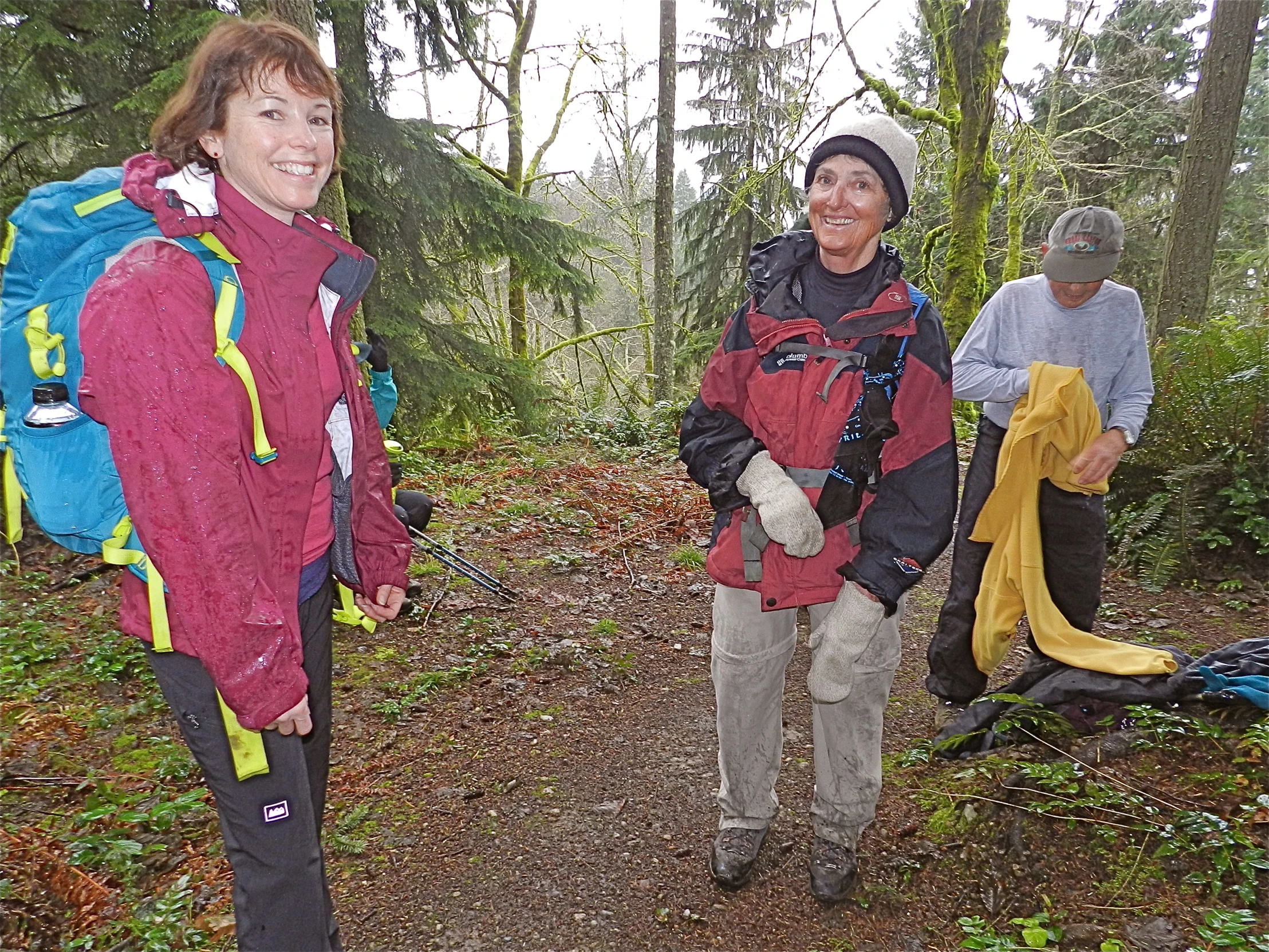 several women stand near a camp site in the woods