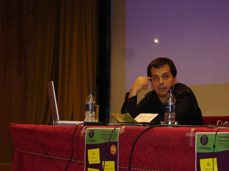 man sitting at a table with a notebook computer in front of him