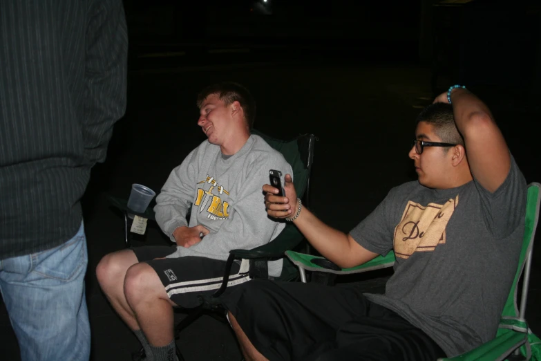 two men laugh as they sit in folding chairs