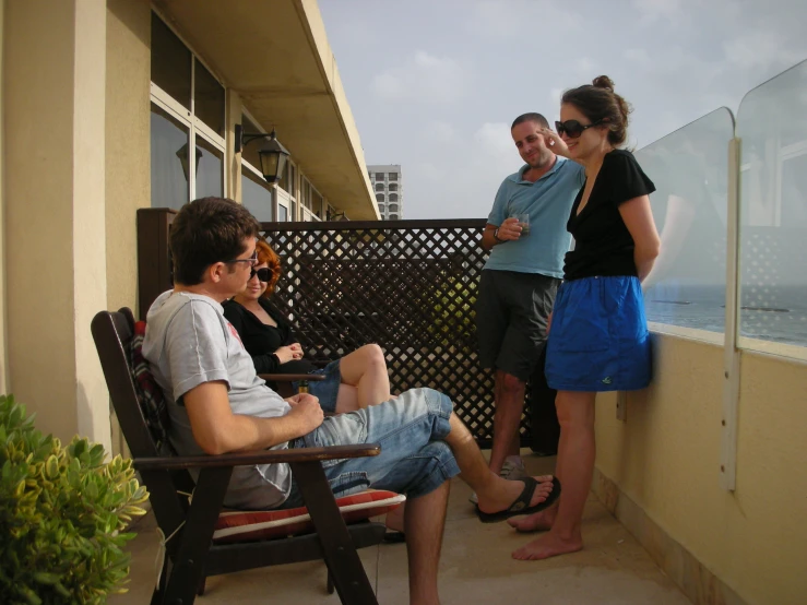 a family sitting outside on the balcony of their apartment