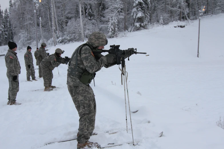 a man holding an akm rifle in a line while standing in the snow