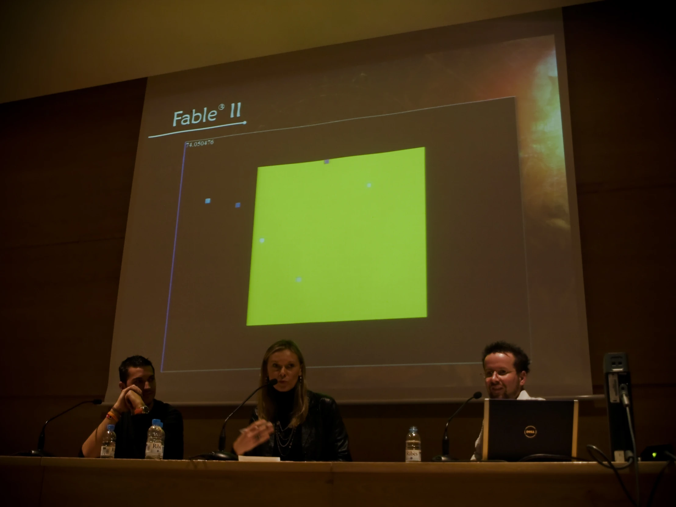 four people in a panel at a table with a projector screen