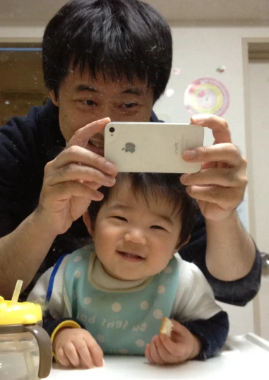 a man holding a baby while holding a smart phone