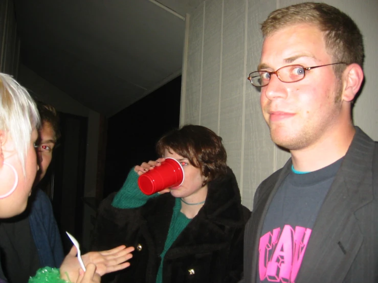 a man drinking from a red cup while standing next to a woman