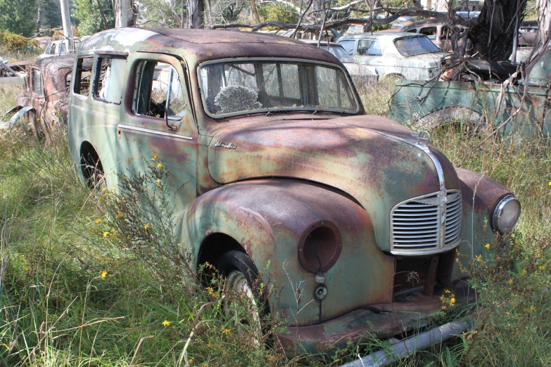 an old rusted out car sitting in the grass