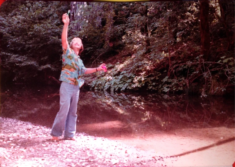 a woman is holding onto soing pink and she is standing in a wooded area