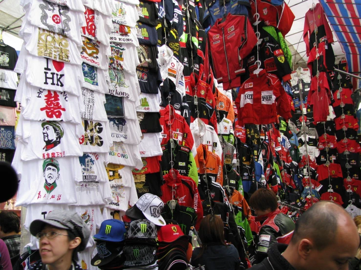 a group of people walking through a store filled with shirts