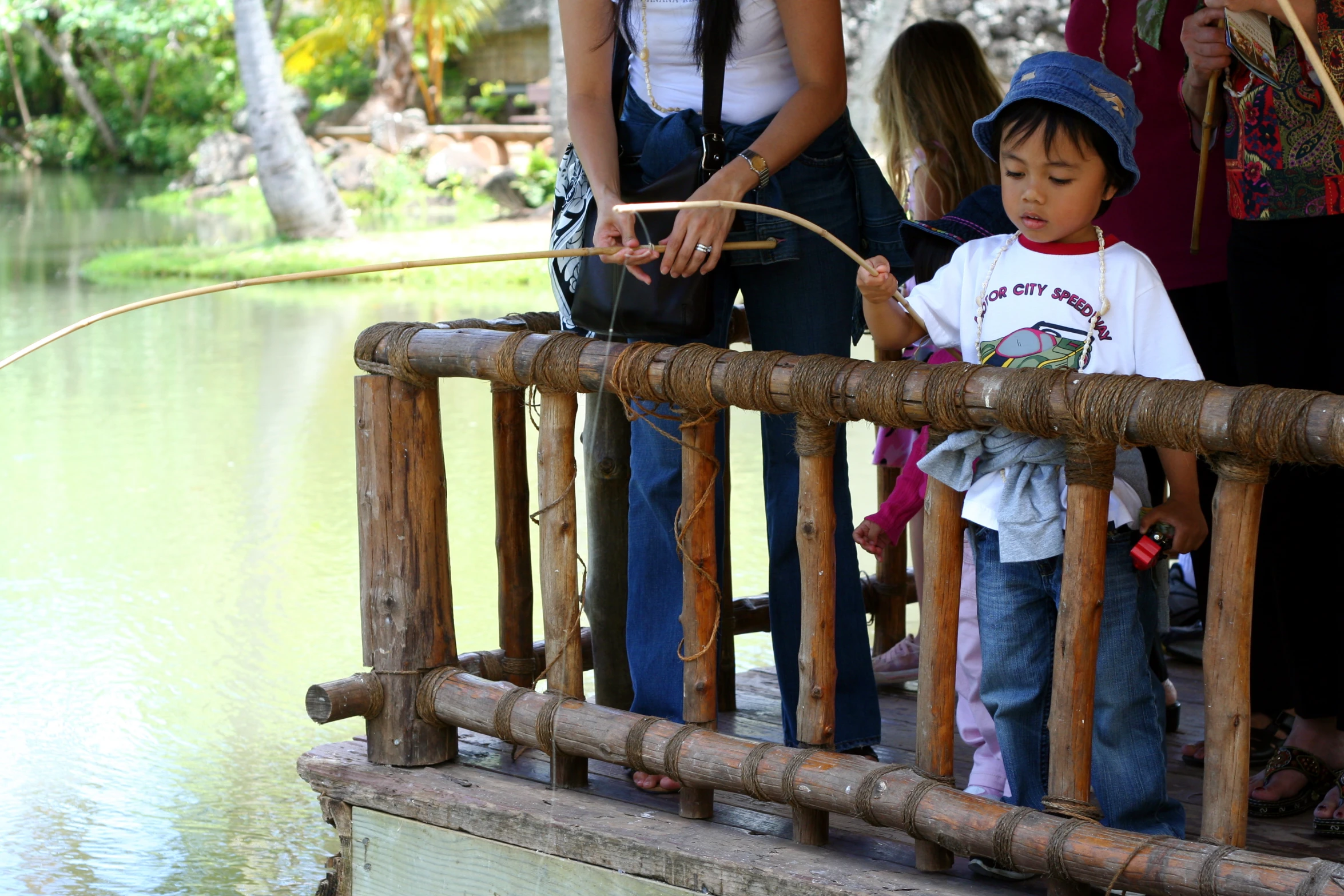 a small child standing on a wooden bridge by the water