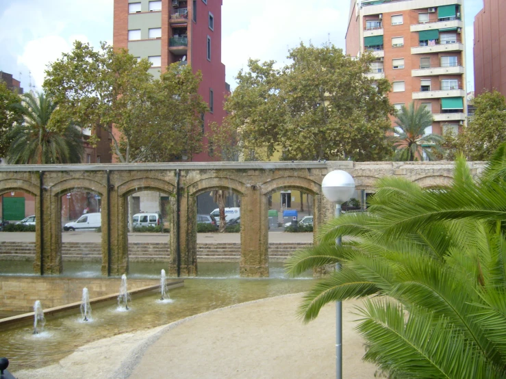 water fountain next to some trees in front of buildings